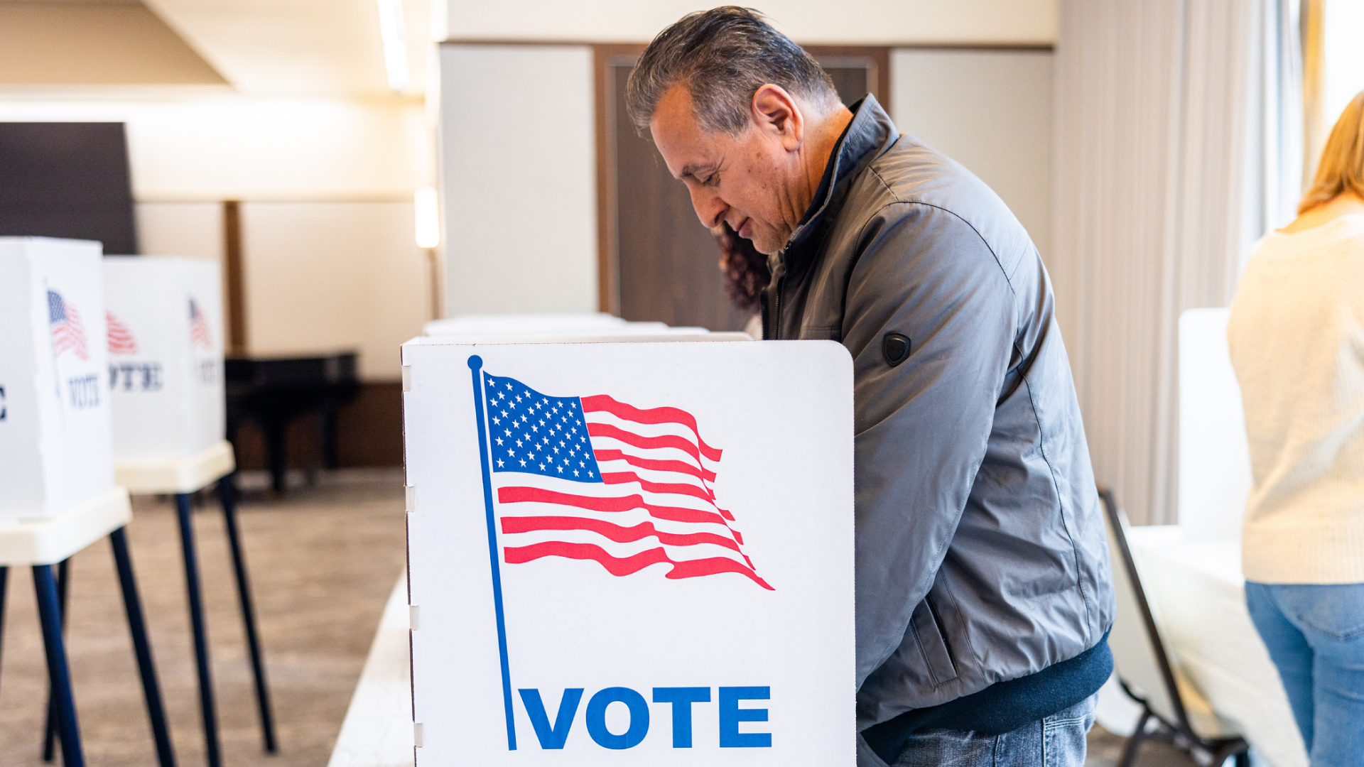 A man voting at a voting booth.